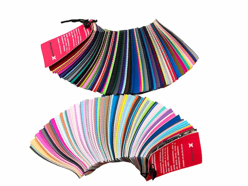 A comprehensive fanned-out display of 300+ neoprene fabric color swatches, showcasing vibrant stock colors and textures available for custom B2B manufacturing