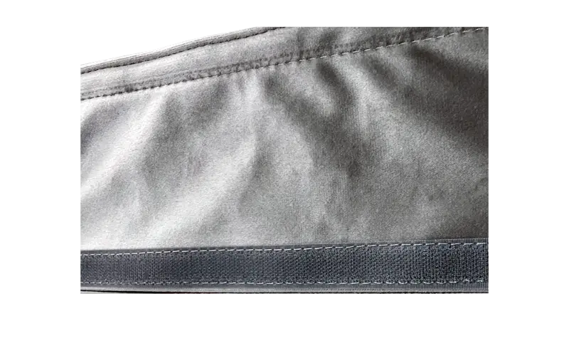 Macro view of clean, straight-line stitching on grey polyester neoprene fabric, demonstrating superior seam strength.
