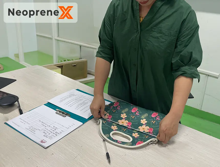 NeopreneX technical specialist performing a detailed quality inspection on a Custom Neoprene Fashion Bag to ensure structural elegance and high-end stitching quality.