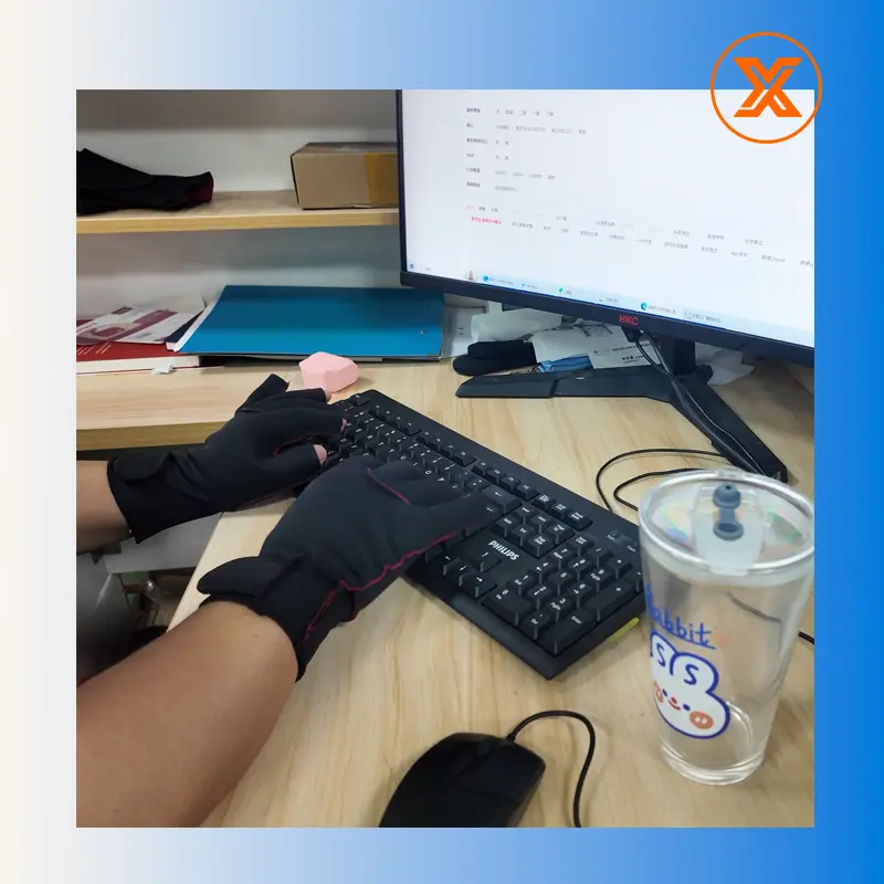 Person wearing NeopreneX compression gloves with Tactile Window design while typing on a computer keyboard to demonstrate precision and carpal tunnel support.