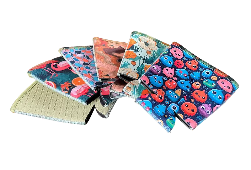 A professional fanned-out display of vibrant monster and floral patterned sublimation coffee sleeves, showcasing high-fidelity print clarity and 4-needle 6-thread flatlock stitching on premium NeopreneX blanks.