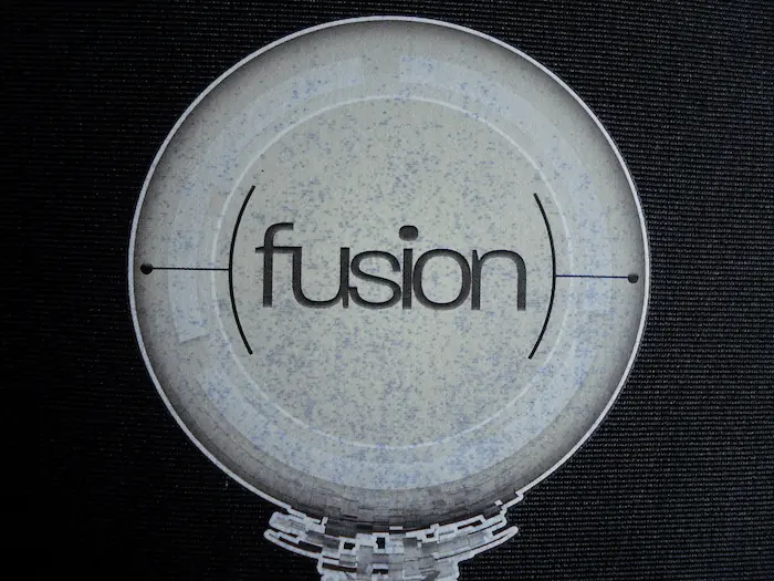 Offset heat transfer printed AMD logo on black Lycra neoprene sleeve showing severe color migration – white text appears gray with dirty edges due to dye sublimation from dark fabric.