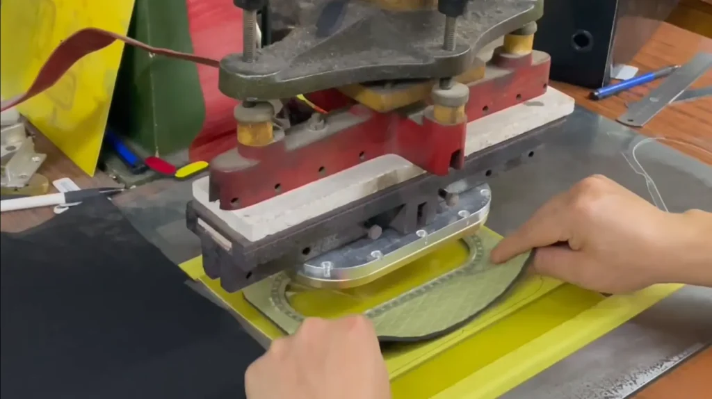 Precision die-cutting process for neoprene fabric, showing the manual handling required for accurate material processing in industrial production.