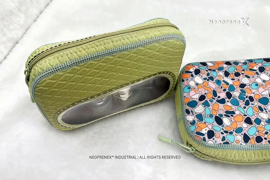Embossed green neoprene travel makeup bag opened with skincare bottles and jars arranged in front