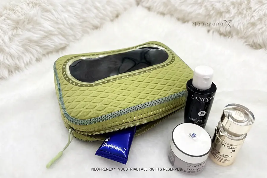 Green embossed neoprene cosmetic bag with large transparent TSA window showing skincare products inside