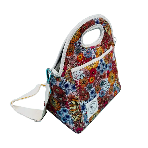 The Sling upgraded neoprene lunch bag featuring vintage floral prints, an external zipper pocket, and a detachable white shoulder strap for flexible carrying options.