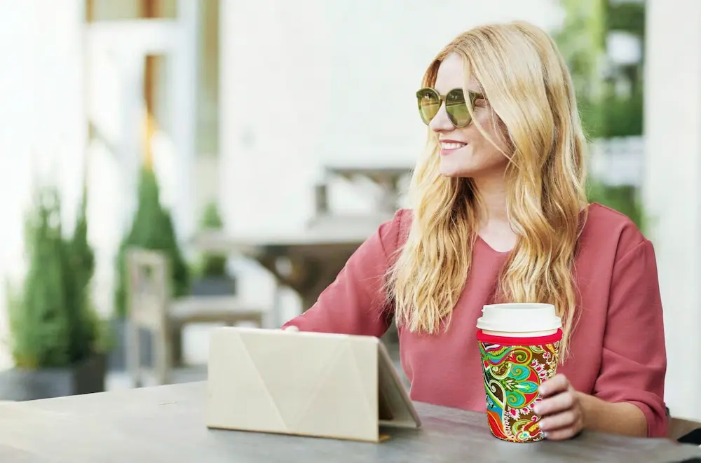 Branded reusable neoprene coffee sleeve used at an outdoor cafe for coffee roasters and lifestyle merchandise collections