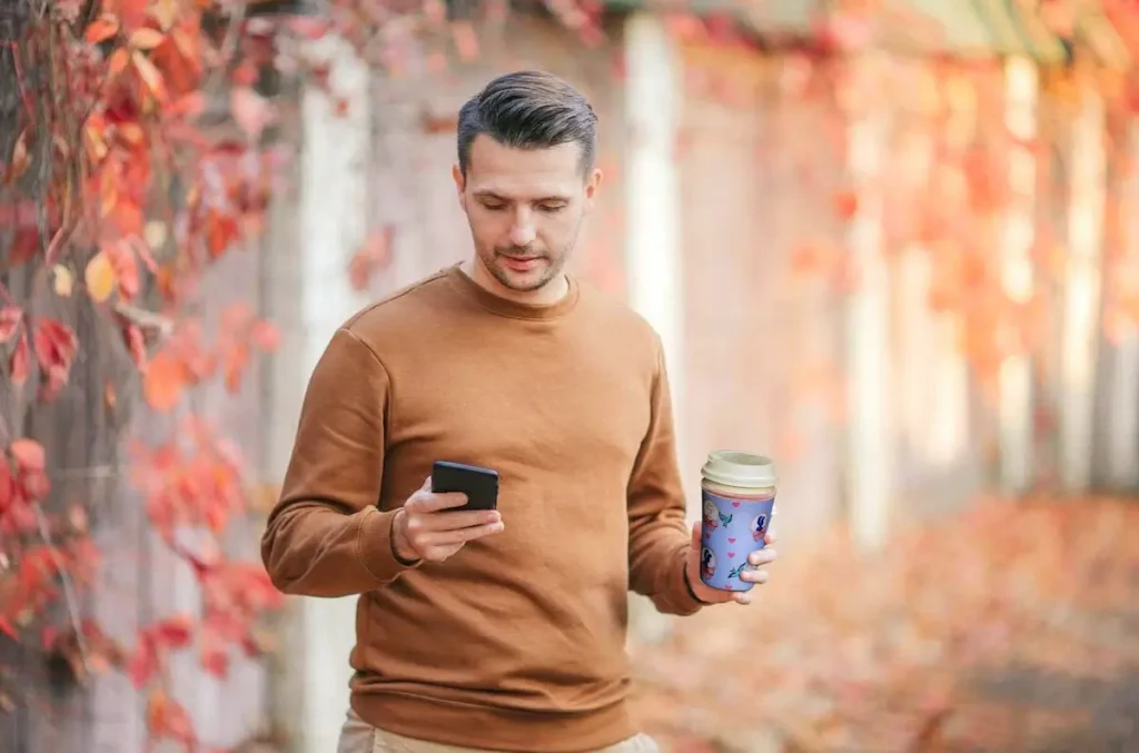 Reusable custom neoprene coffee sleeve in everyday use by consumer holding takeaway beverage cup